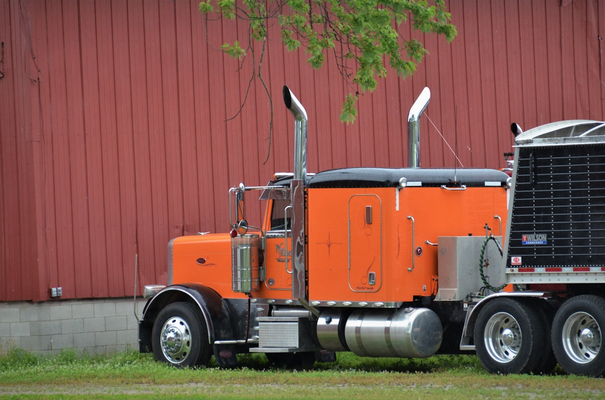an orange semi truck parked in front of a red building