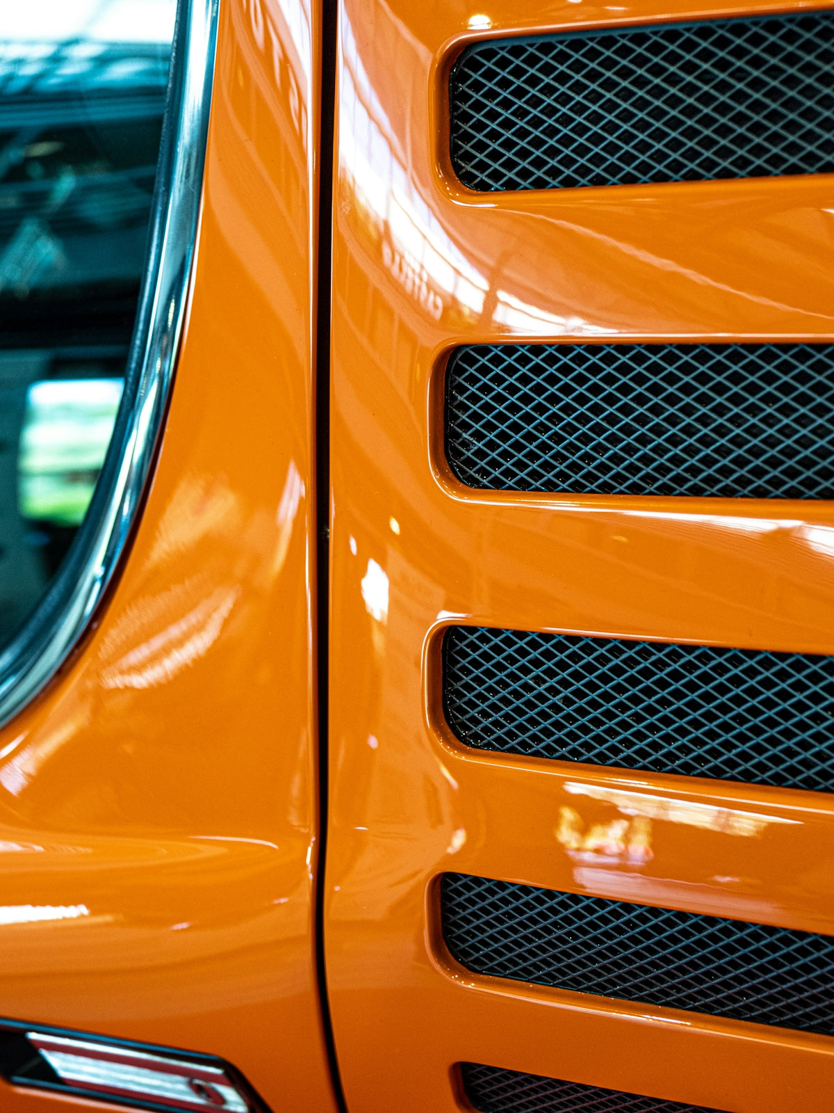 Bright orange vehicle exterior detail with grilles.