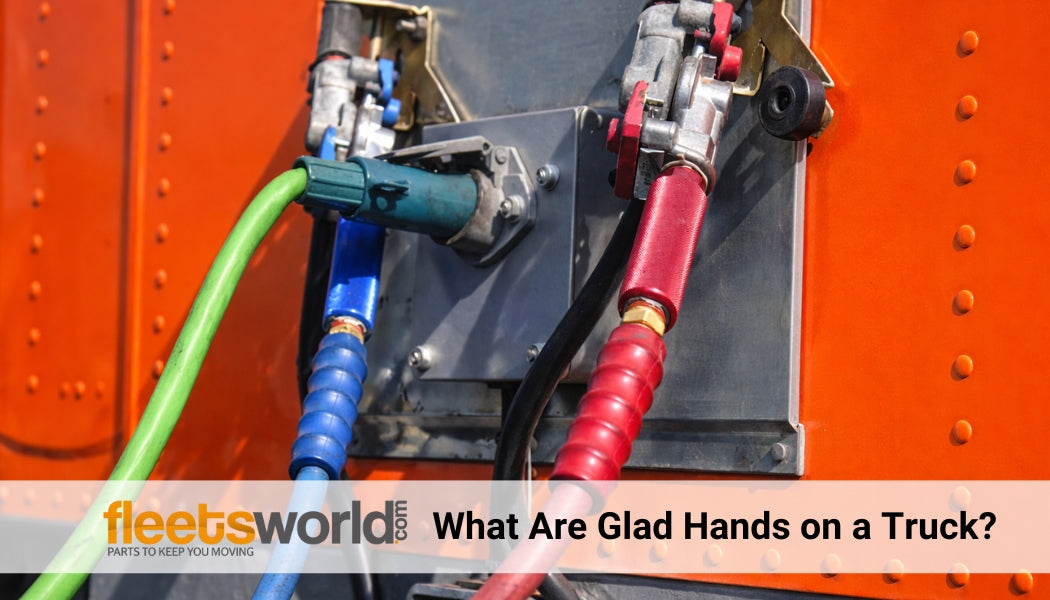 Close-up of truck glad hands connected to red and blue air brake hoses on the back of an orange semi truck, showing air line connections between tractor and trailer.